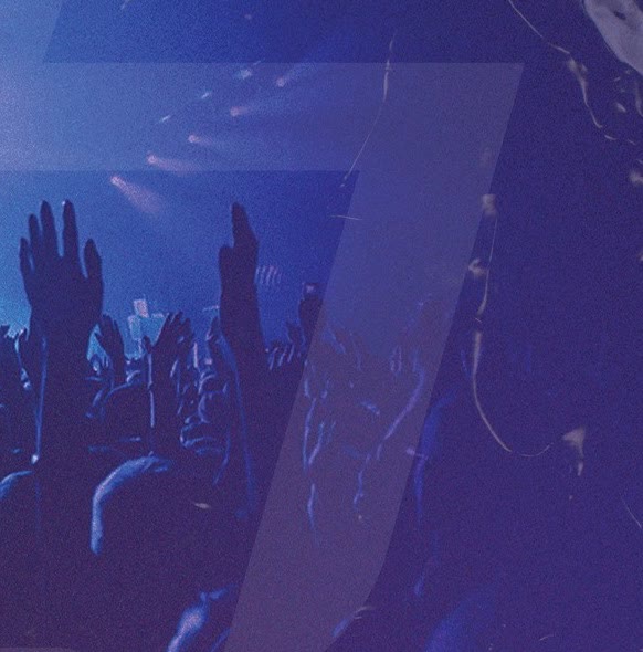 A crowd with their hands up under the stage lights